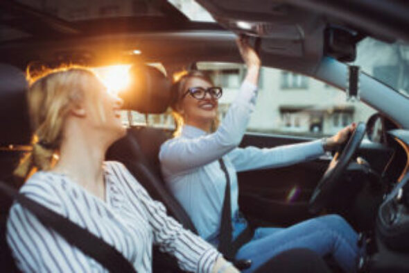 Two female friends enjoying road trip traveling at vacation in the car